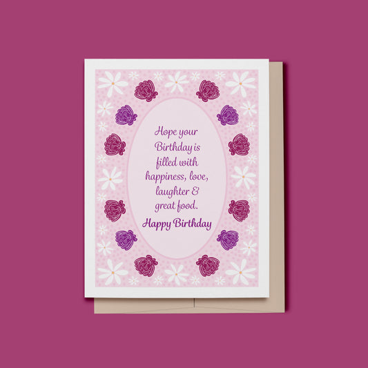 A pretty feminine floral Happy Birthday card featuring script text which reads, Hope your Birthday is filled with happiness, love, laughter and good food on a pastel pink polka dot background.