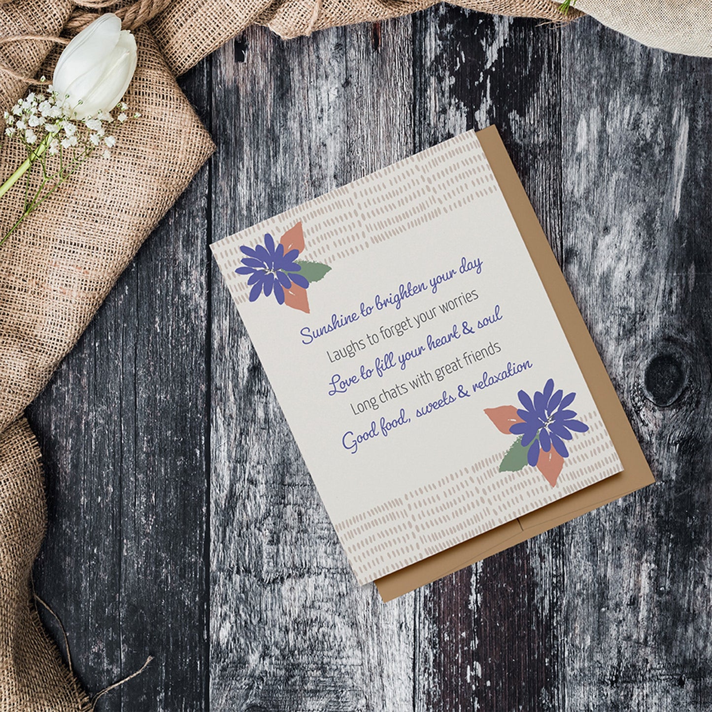 A Good Day Card with a light beige background, this card features a layered look with periwinkle colored flowers with peach and green leaves, a border at the top and bottom made out of many marks that are a darker shade of beige, and text which is a mix of script and sans serif which reads, "Sunshine to brighten your day, Laughs to forget your worries, Love to fill your heart & soul, Long chats with great friends Good food, sweets & relaxation."