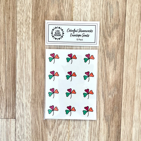 Photo of one package of colorful shamrock envelope seals in cello packaging on a wooden background.