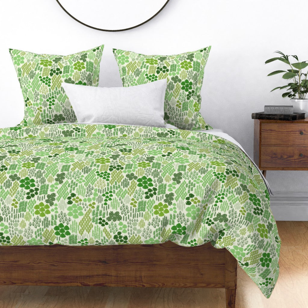 Irish Green Mosses pattern design shown on bedding and pillows in a bedroom setting.