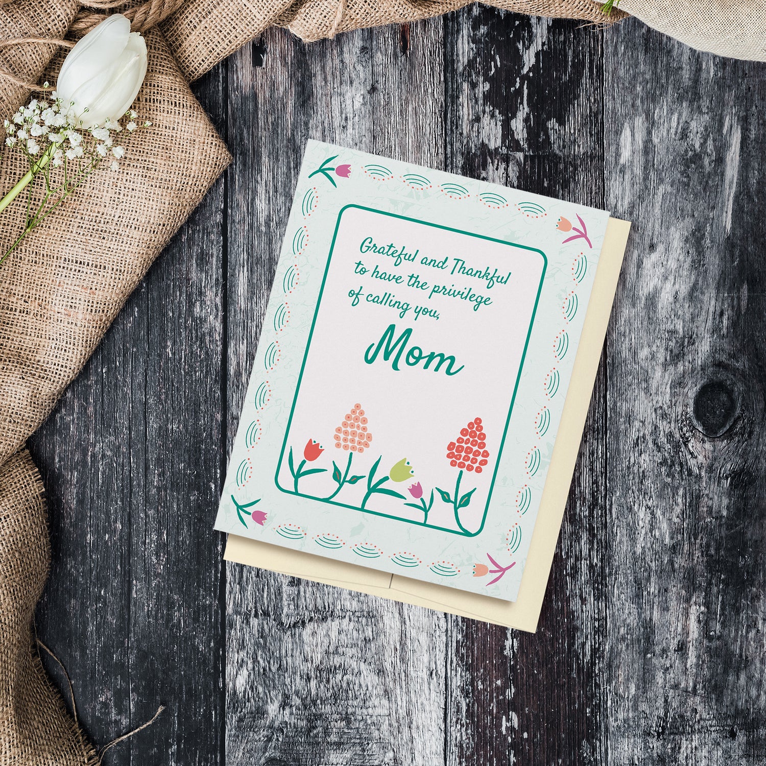 Grateful and thankful to have the privilege of calling you, Mom, greeting card displayed on a wood background surrounded by flowers and fabric.