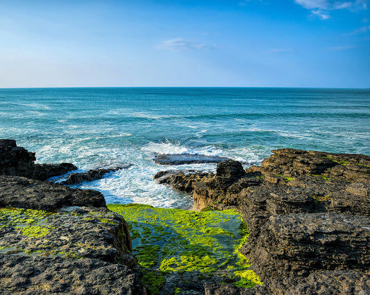 Ireland Photography featuring Sligo Bay with bright green moss on the rocky shore bathing in the crashing waves against a beautiful bright blue sky. 