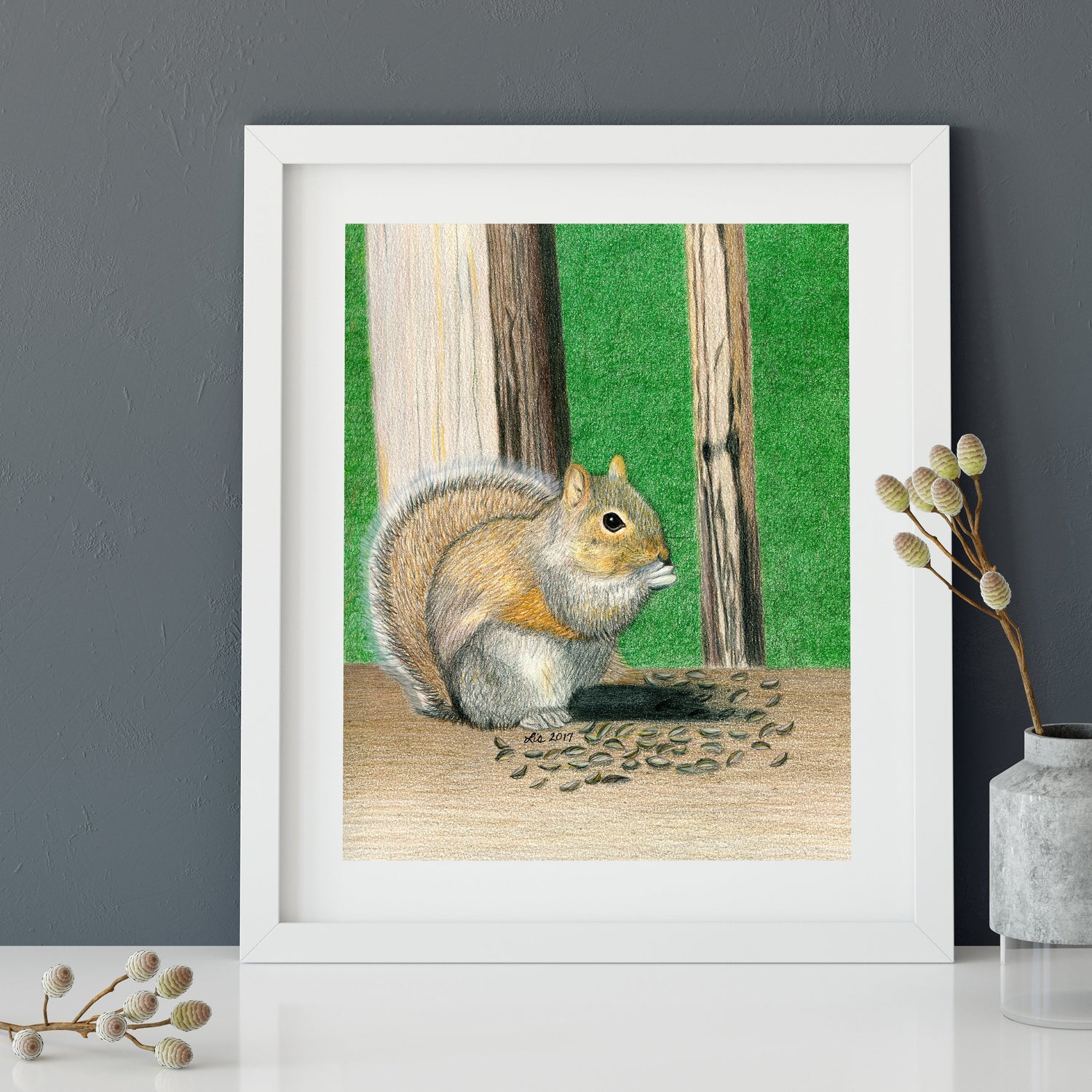 Framed art print of a colored pencil drawing reproduction of a squirrel eating seeds on a backyard deck.